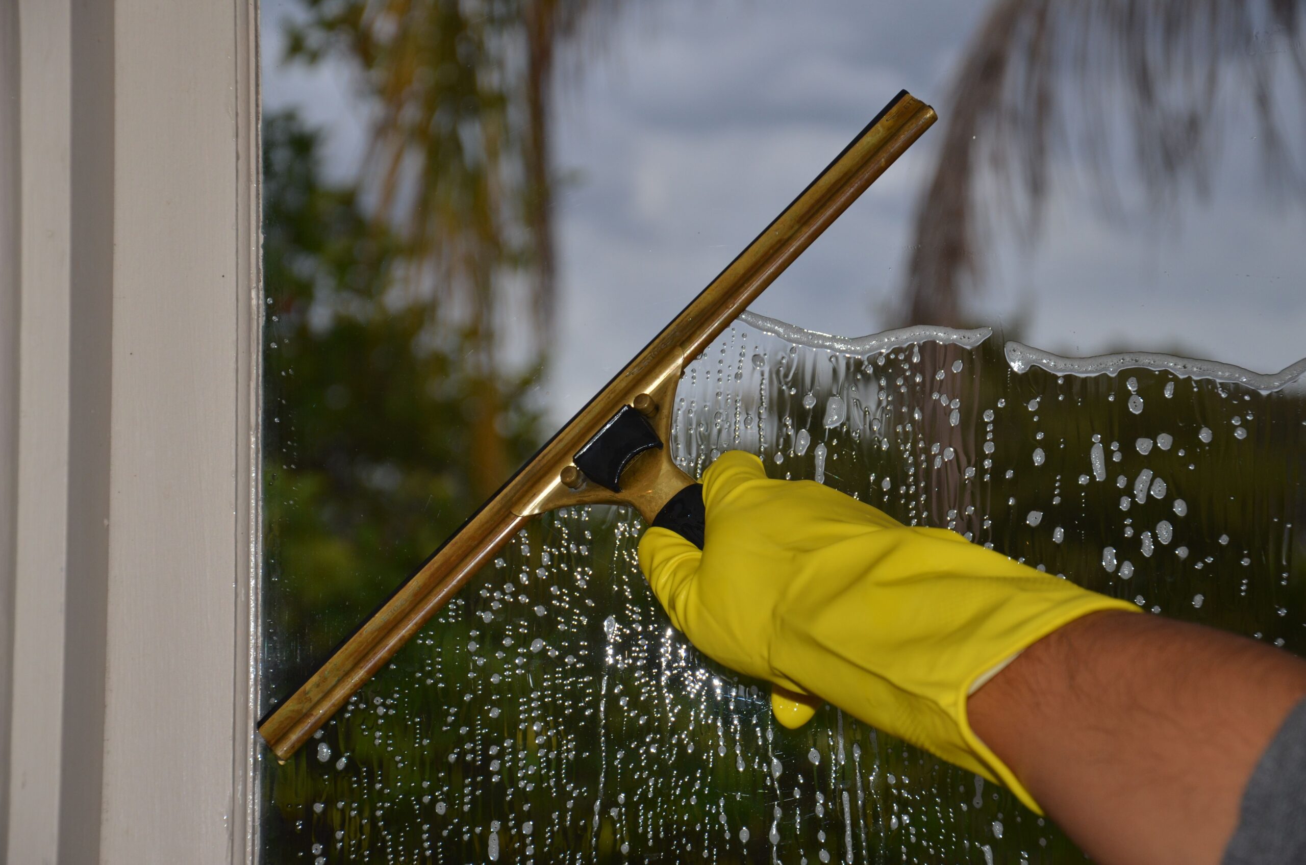 Fensterreinigung mit goldfarbenem Fensterwischer